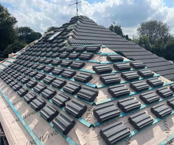 This is a photo of a new hip roof being installed. New felt, battens, and grey tiles have been installed, also a new velux window. Works carried out by CNB Roofing Pontefract